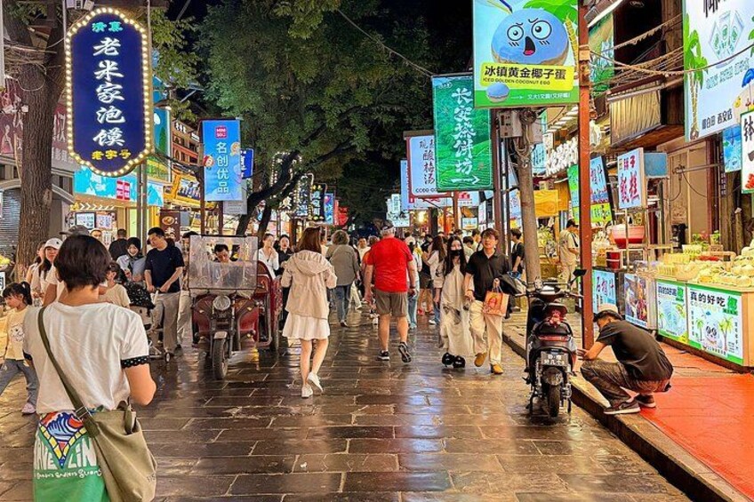 Un mercado callejero animado de noche, con gente caminando y vendedores ofreciendo productos. 2