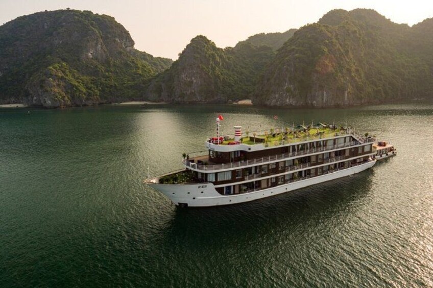 A large riverboat on calm water with lush green hills in the background. 1