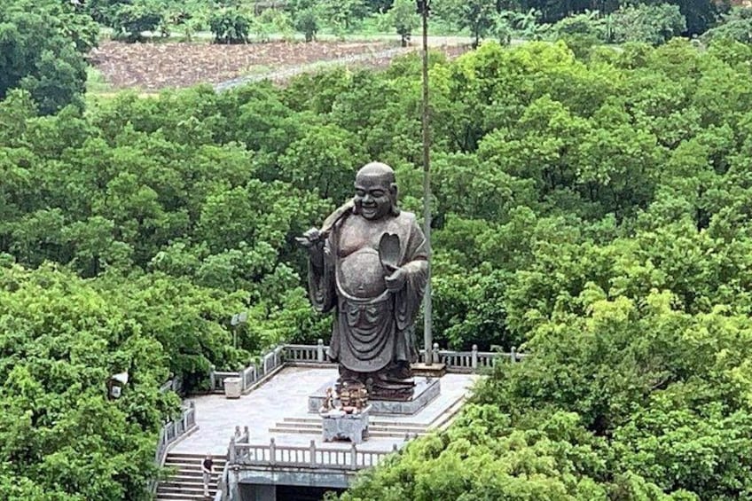 A large Buddha statue on a platform surrounded by lush greenery. 3