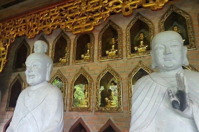 Large white statues with golden frames and a brick wall with arched windows. 5
