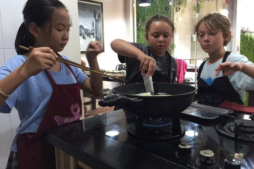 Drei Personen kochen in einer Küche, ein Kochtopf steht auf dem Herd. 3