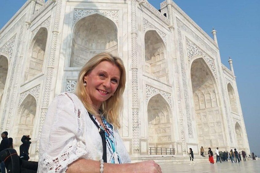 A person standing in front of the Taj Mahal with its intricate white marble architecture. 3