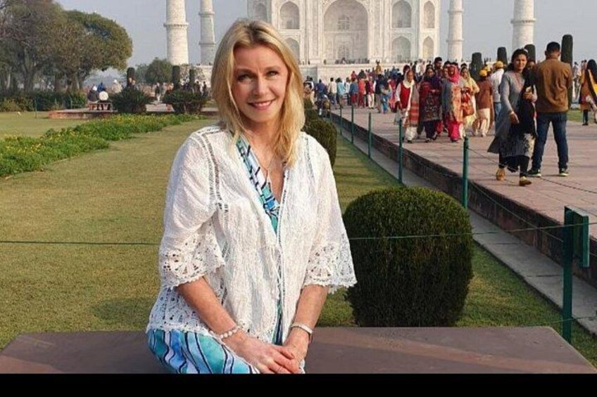 A person sitting on a bench with the Taj Mahal in the background. 2