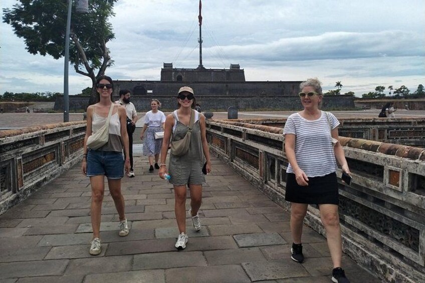 A group of people walking on a stone bridge with a historical structure in the background. 4
