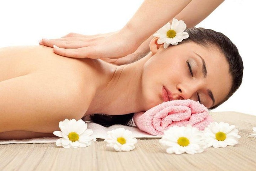 Una persona recibiendo un masaje en la espalda con flores blancas y una toalla rosa. 3