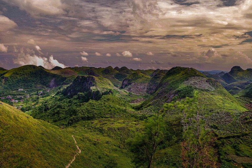 A mountainous landscape with a winding path, lush greenery, and a cloudy sky. 4