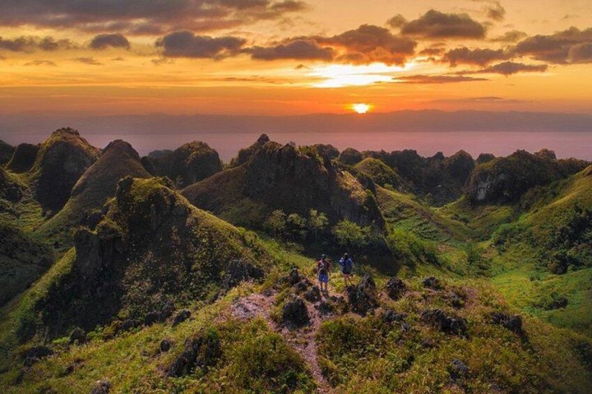 A mountainous landscape with hikers at sunset. 1