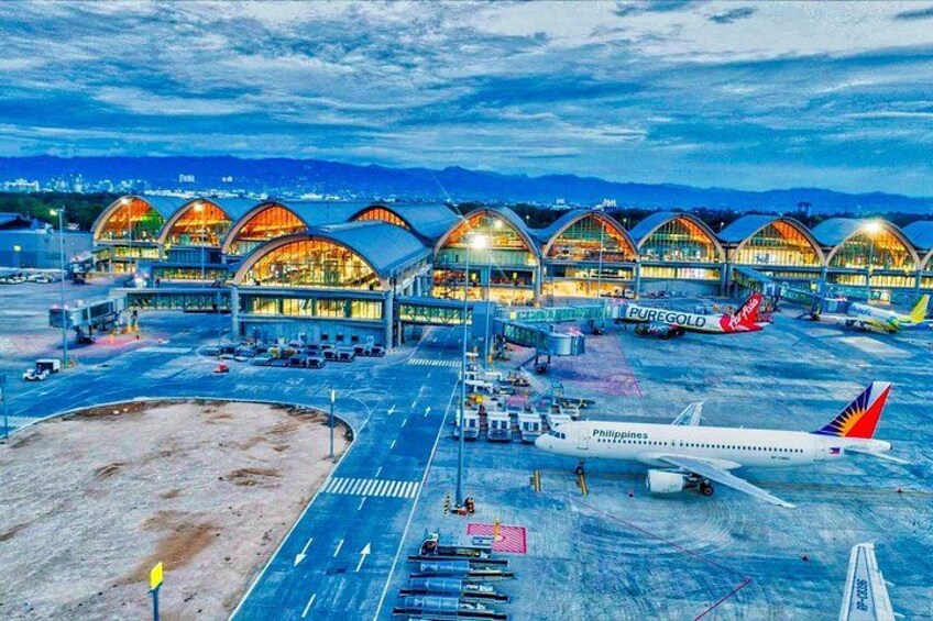 An airport with multiple terminal buildings, parked airplanes, and a clear sky. 2