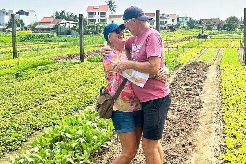 Two people standing in a field with rows of crops. 2