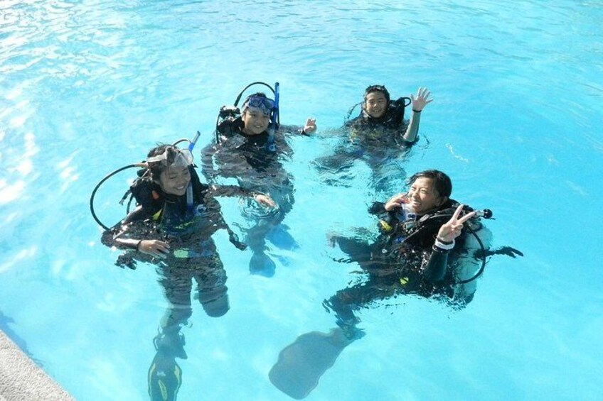 Four people in a swimming pool wearing scuba diving gear. 1