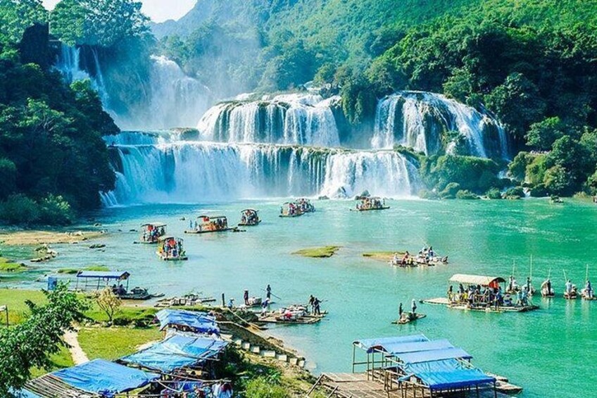 A waterfall, boats, and a riverbank with structures. 1