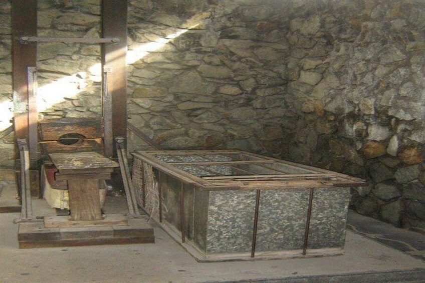 Eine Steinmauer, eine Holzbank und eine Steinstruktur mit Metallgestell. 2