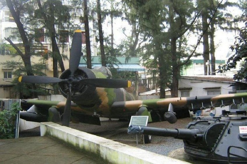 Ein ausstellendes Militärflugzeug, umgeben von Bäumen und Gebäuden. 5
