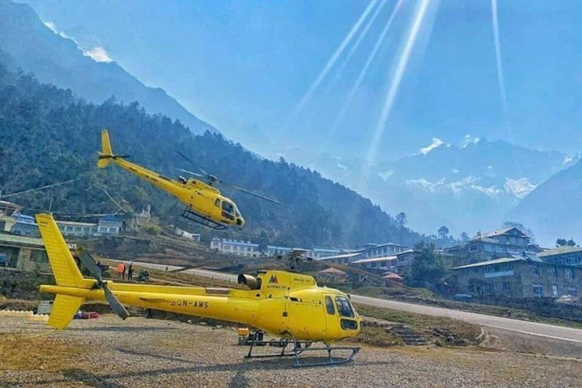 To gule helikoptere på en landingsplads med et bjergrigt landskab i baggrunden. 5