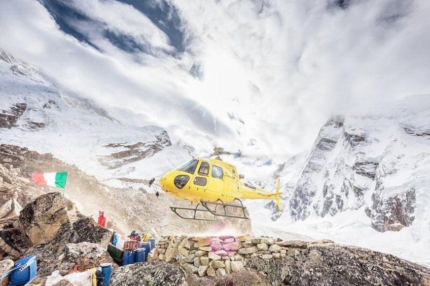 En gul helikopter på et snøklædt bjerg med stengrund og et flag. 3