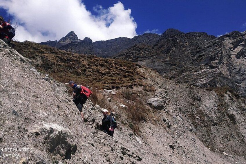Hikers on a rocky mountain trail with a clear sky and distant mountains. 3