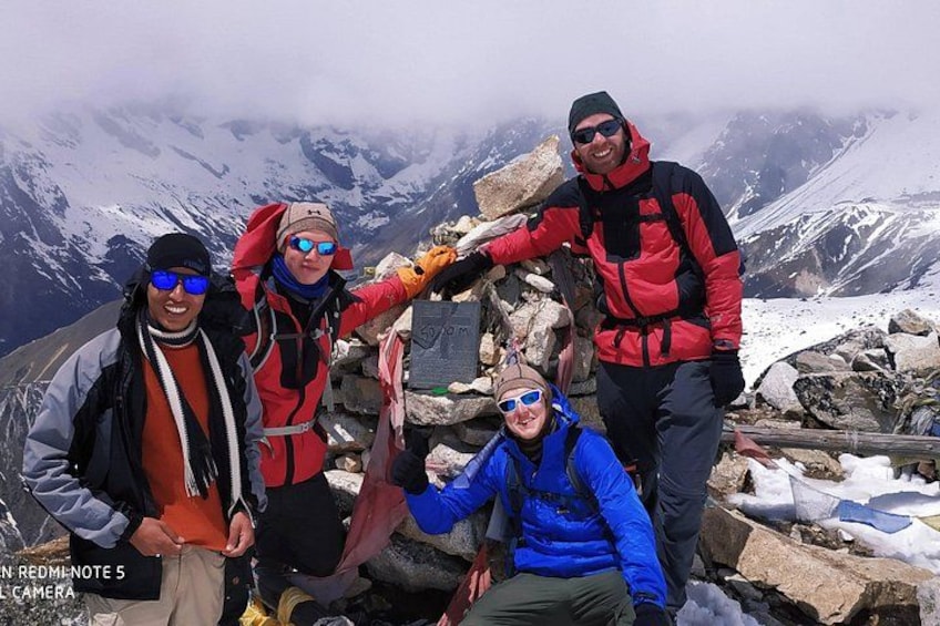 A group of people on a mountain peak with snow-covered terrain and rocky outcrops. 1