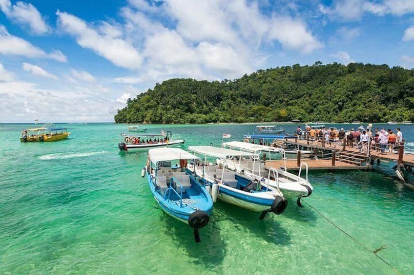 Une mer turquoise aux eaux limpides, où des bateaux sont amarrés à un quai, le tout entouré de collines verdoyantes. 4