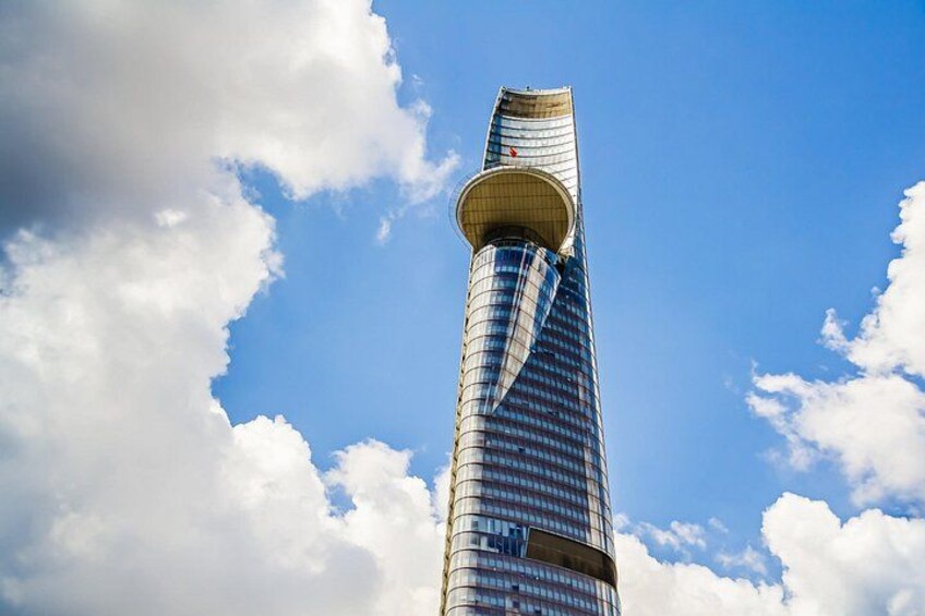 A tall skyscraper with a unique twisted design against a blue sky with clouds. 2