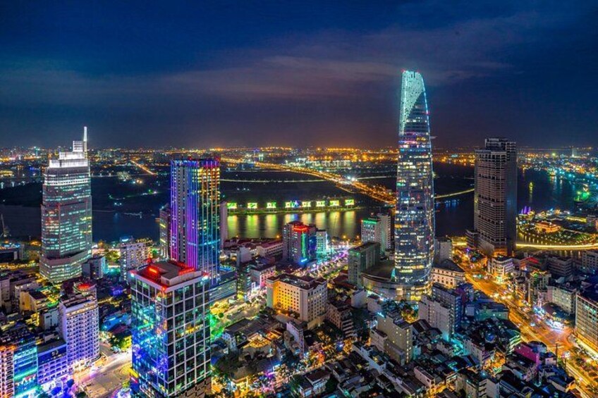 A cityscape at night with illuminated skyscrapers and a river. 1