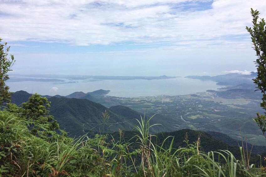 A mountainous landscape with dense vegetation and a distant view of a coastline. 1