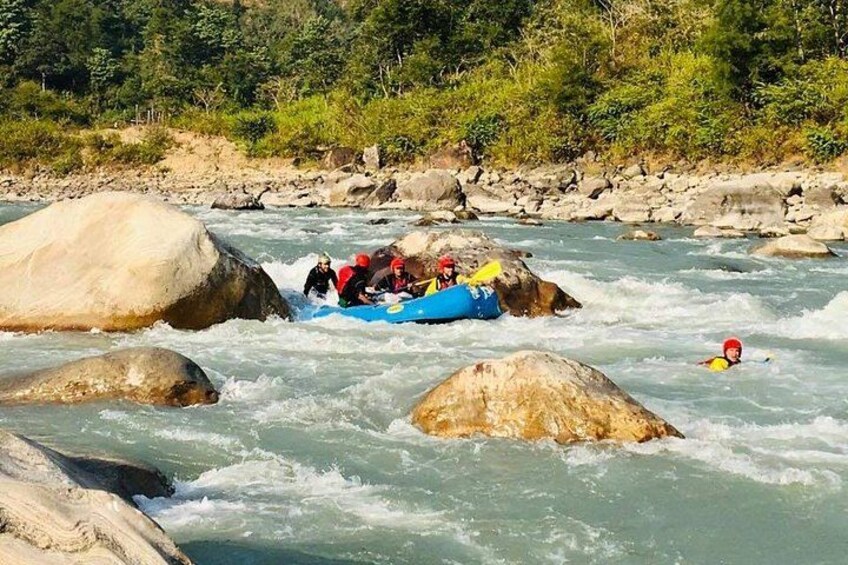 A group of people rafting on a river with large rocks. 2