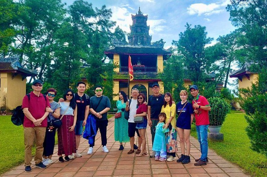 Un grupo de personas frente a un edificio tradicional con techo al estilo pagoda, rodeado de follaje. 5
