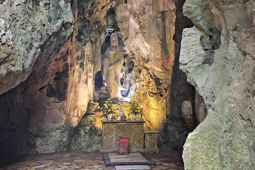 Interior de una cueva con una estatua de Buda, un pequeño altar y una esterilla para orar. 1