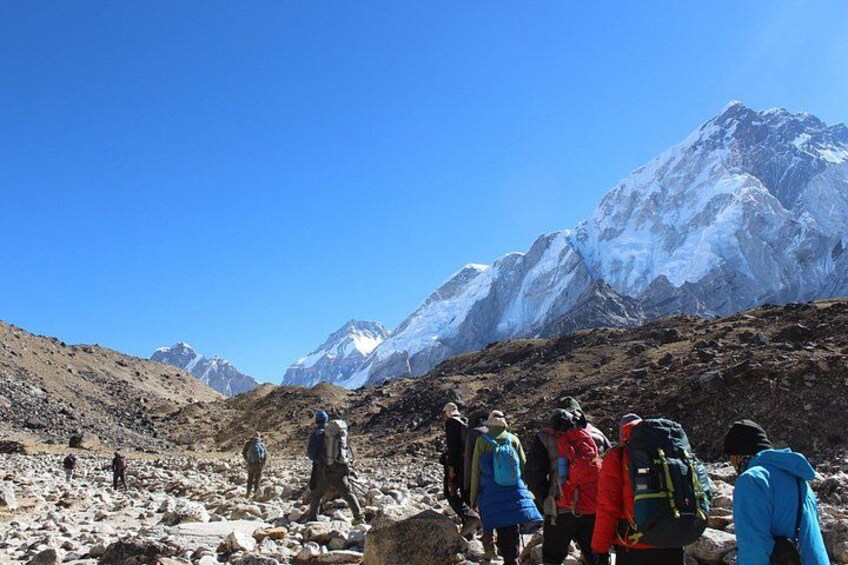 A group of hikers on a rocky mountain trail with snow-capped peaks in the background. 3
