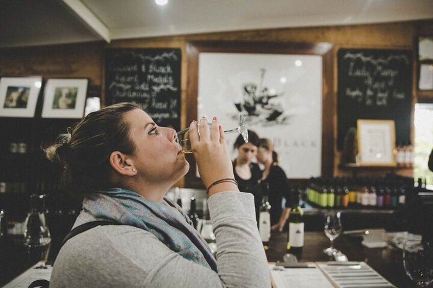 En person som dricker ur ett glas på en restaurang, med en meny skriven på en svart tavla i bakgrunden. 2