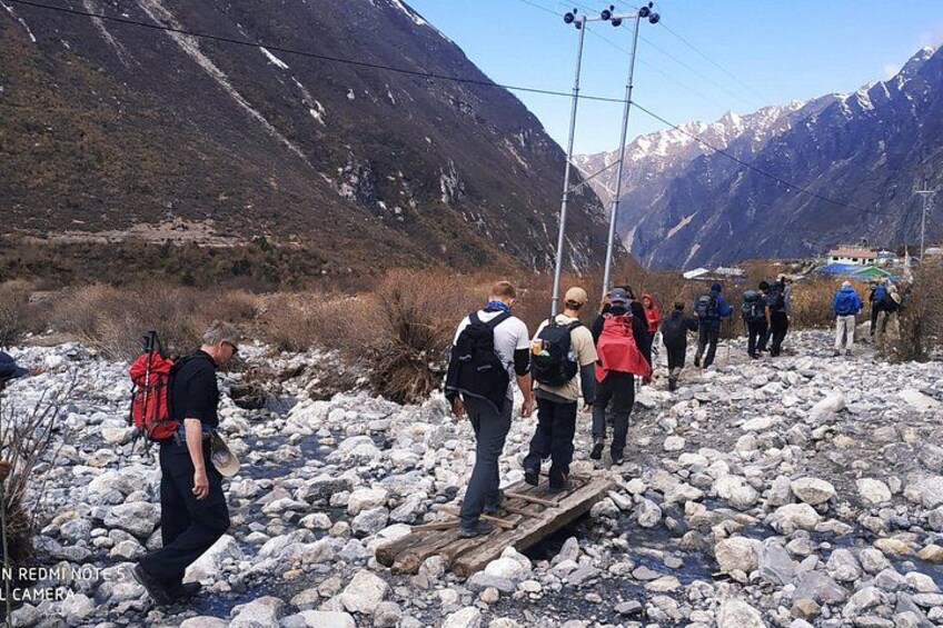 A group of hikers crossing a rocky stream in a mountainous area. 3