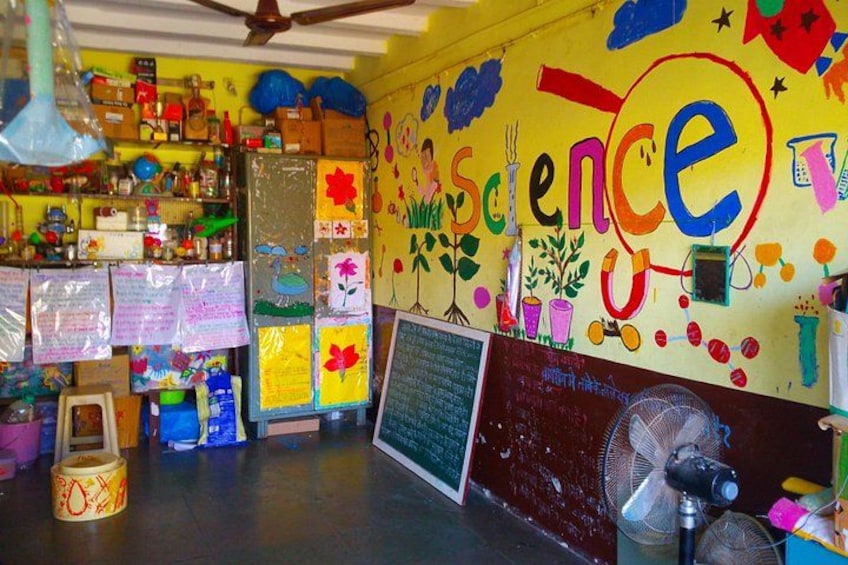 Un aula colorida con carteles educativos, una pizarra y diversos objetos relacionados con la ciencia en estanterías. 3
