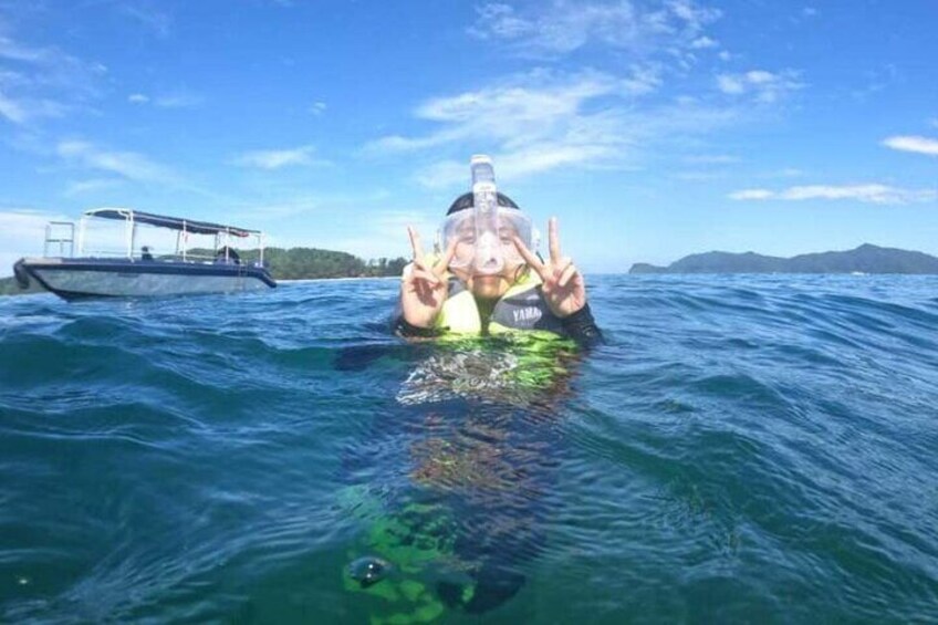 A person swimming in the ocean with a boat in the background. 5