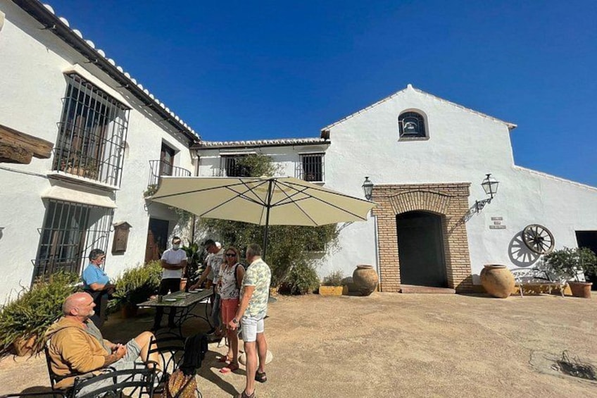 A white building with a clock, a large umbrella, and people gathered outside. 3