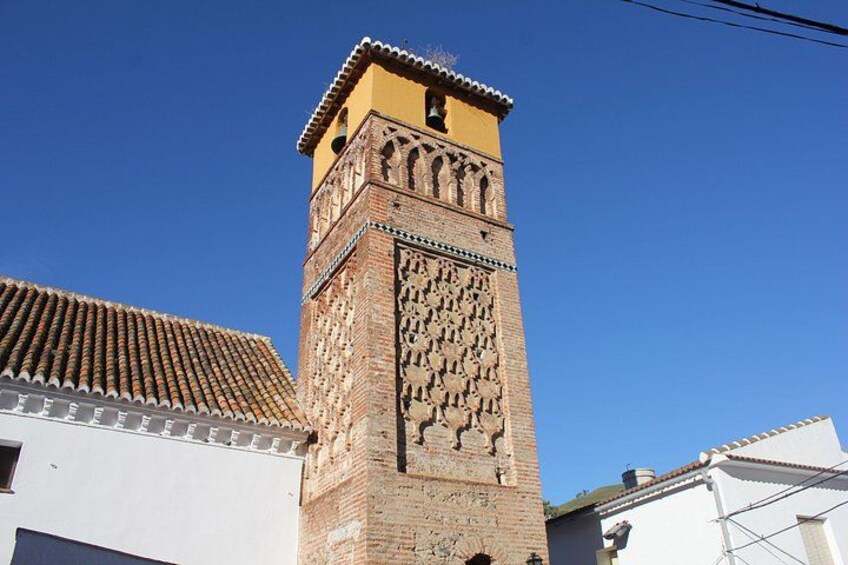 A tall tower with intricate brickwork and a yellow top. 1