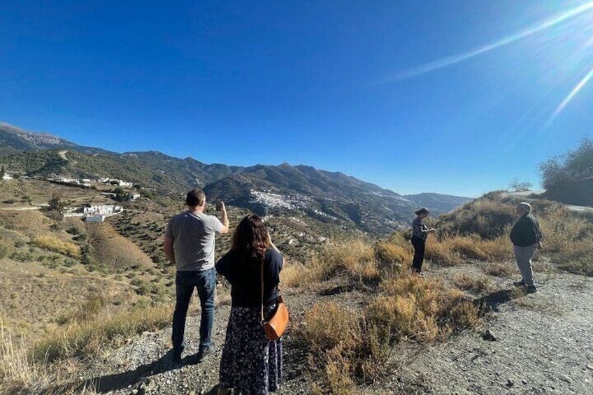 A group of people standing on a dirt path overlooking a mountainous landscape with a clear sky. 4
