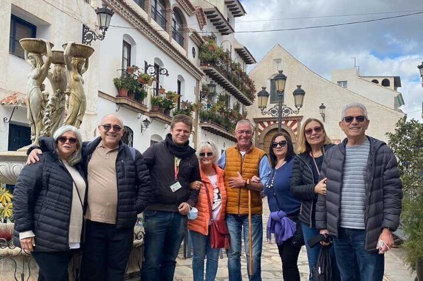 A group of people standing in front of a building with a fountain and decorative statues. 5