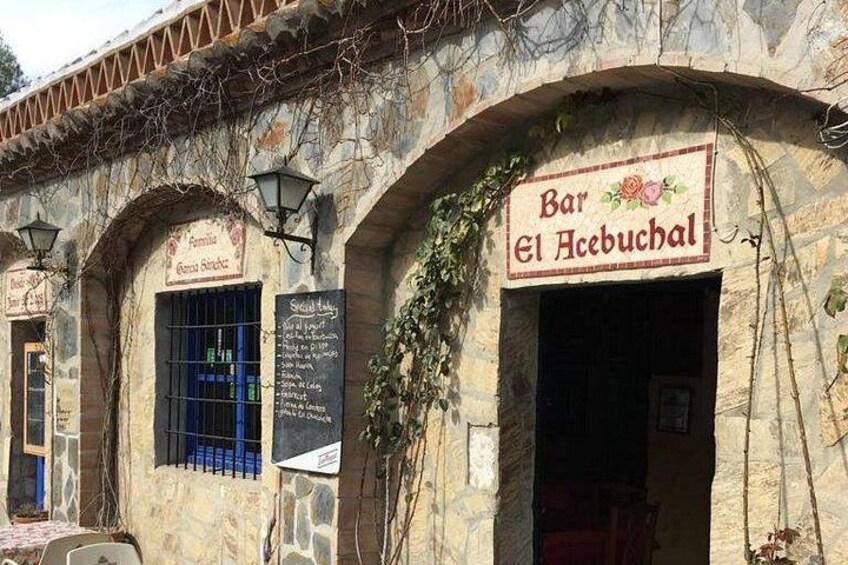 Ein Steinhaus mit einem Schild für 'Bar El Acebuchal' und einer Speisekarte. 5