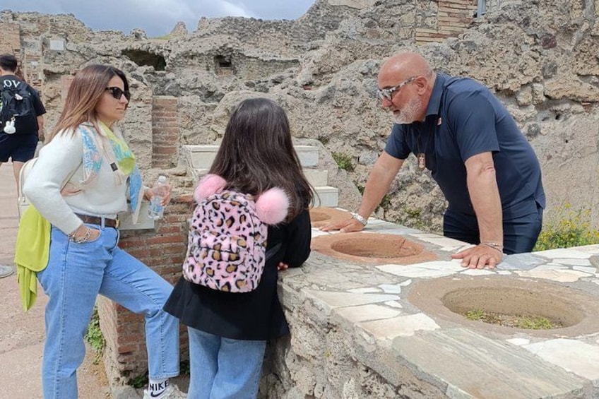 Mensen bij een archeologische plek met ruïnes en een stenen constructie. 5