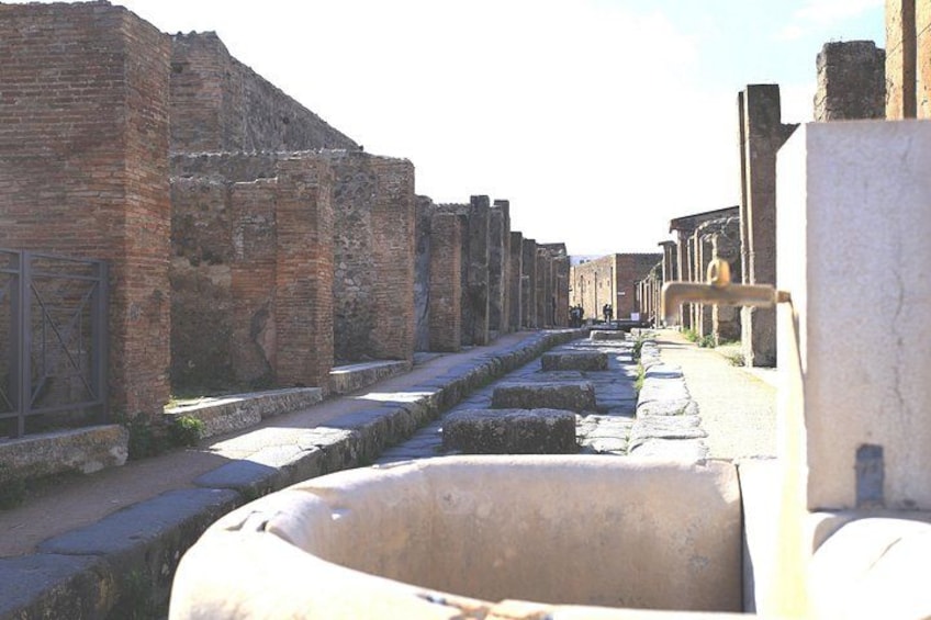 An ancient Roman street with brick walls and stone paving. 2