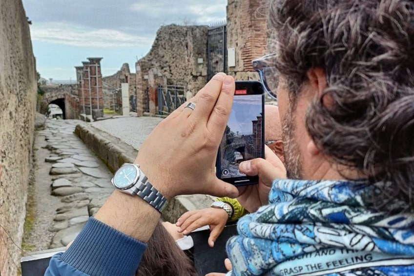 Iemand maakt een foto met een smartphone in een oude ruïne met stenen paden en oude gebouwen. 2
