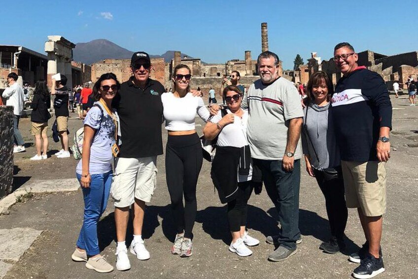 A group of people posing in an outdoor setting with historical ruins and a volcano in the background. 3