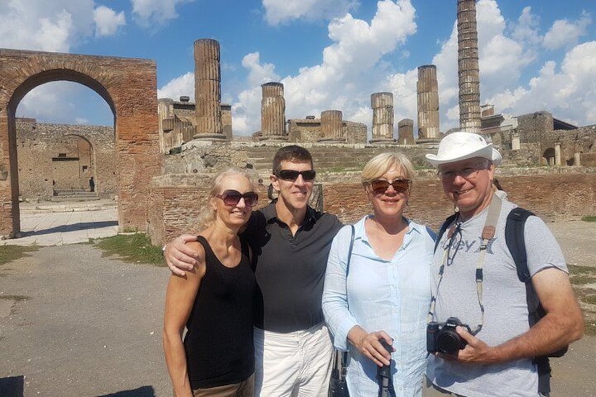 A group of people standing in front of ancient ruins with columns and an archway. 2