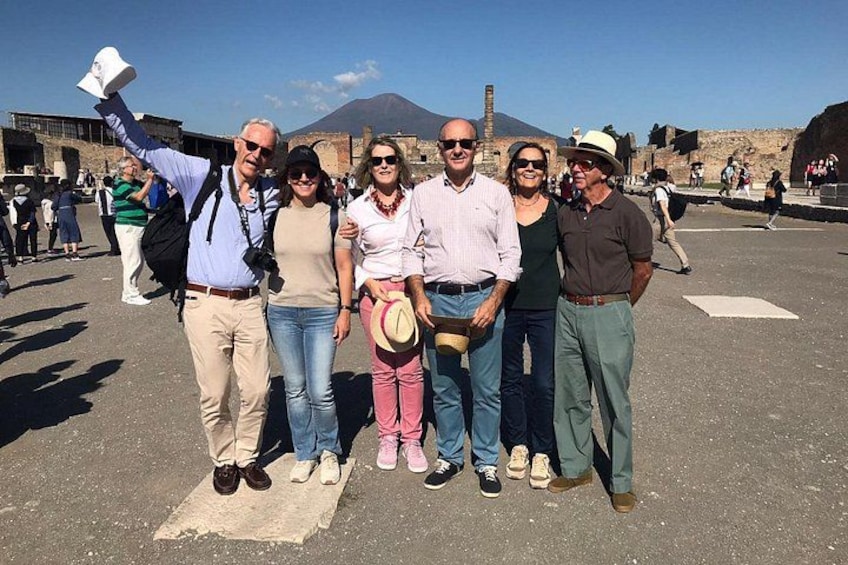 A group of people posing for a photo in an outdoor setting with historical ruins and a volcano in the background. 4