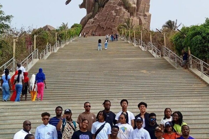 A group of people standing on a staircase leading up to a large rock formation. 3