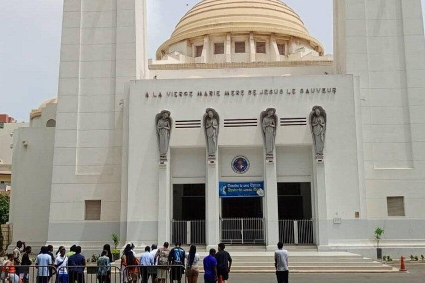 A large white building with a dome and columns, featuring a sign with French text. 2