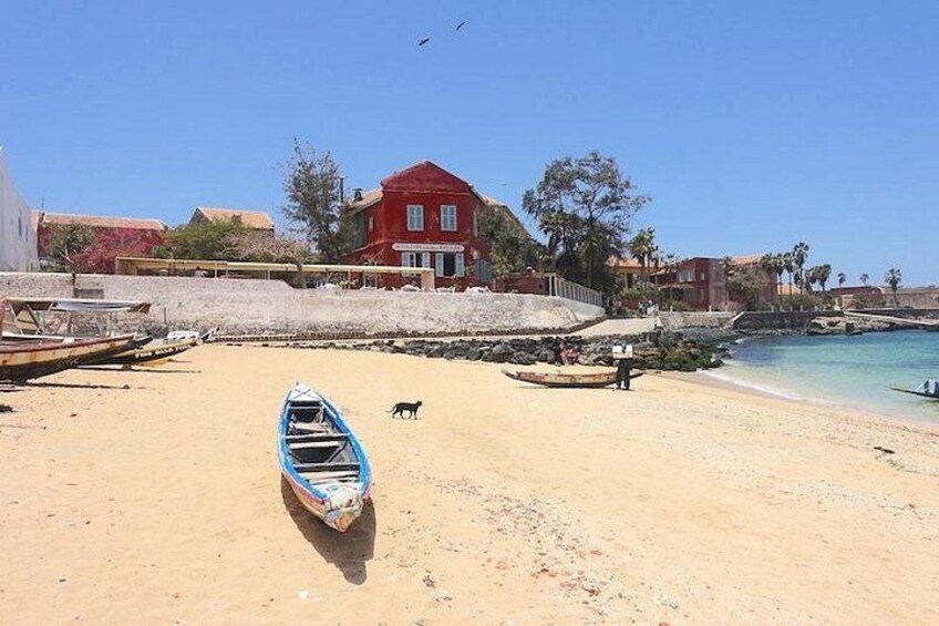 A sandy beach with a blue boat, a red building, and a calm sea. 4