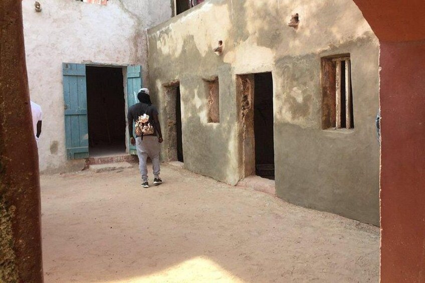 A narrow alleyway with buildings, one with a blue shutter and another with a door. 5