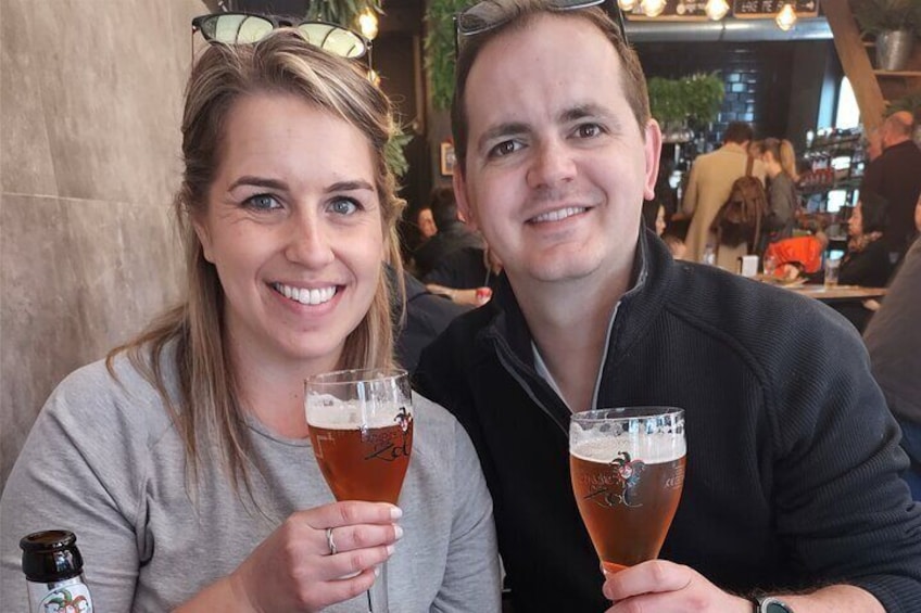 Two people holding glasses of beer at a bar. 3