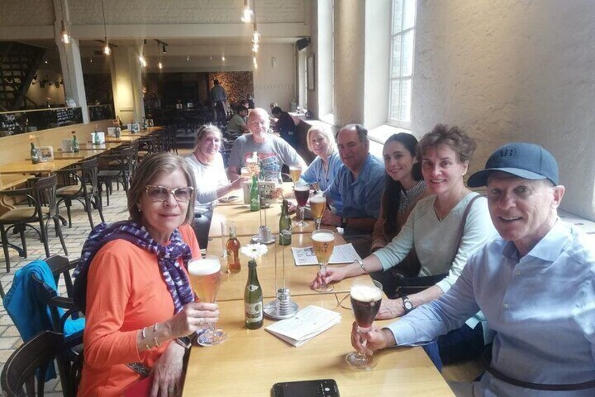 Een groep mensen zit rond een tafel in een restaurant, met bierglazen in hun handen. 5